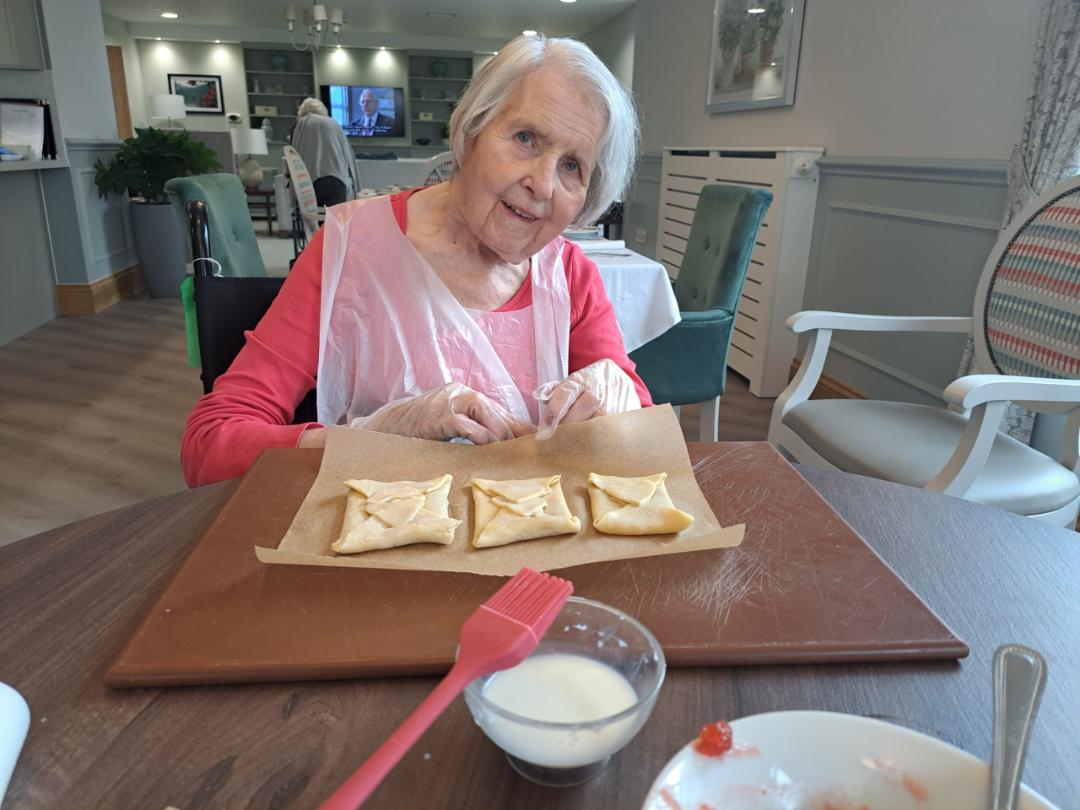 A female resident smiling with some pastries she has been making.