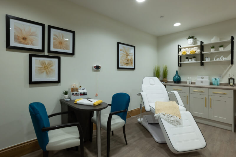 A nail desk and a beauty chair for facial treatments. Flower prints on the wall.