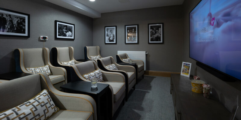 Cinema room. Seven armchairs. Photos on wall. Patterned cushions. Large flat screen TV.