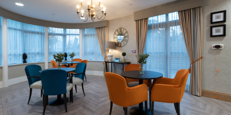 Dining room with three table with orange and blue chairs.