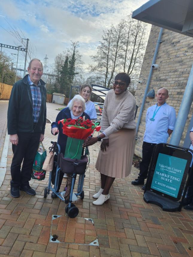 A female resident with rose given to her by the home manager.