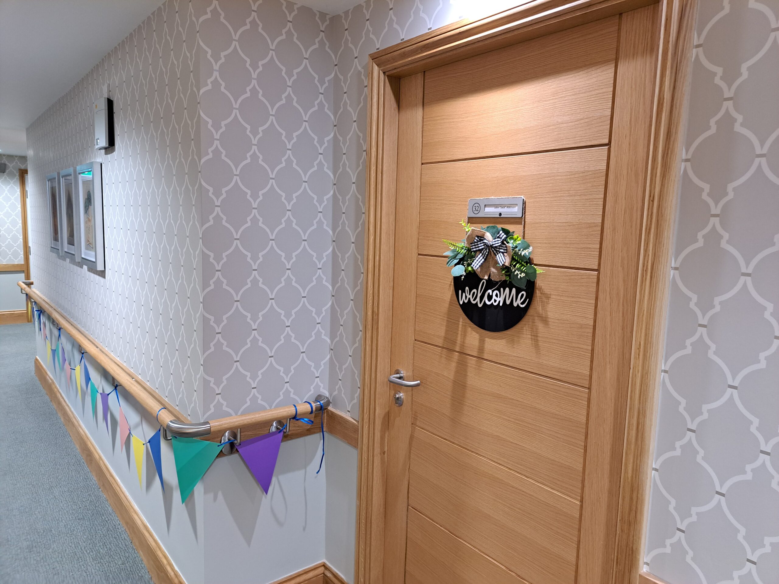 A oak door with a welcome sign and bunting on handrails.