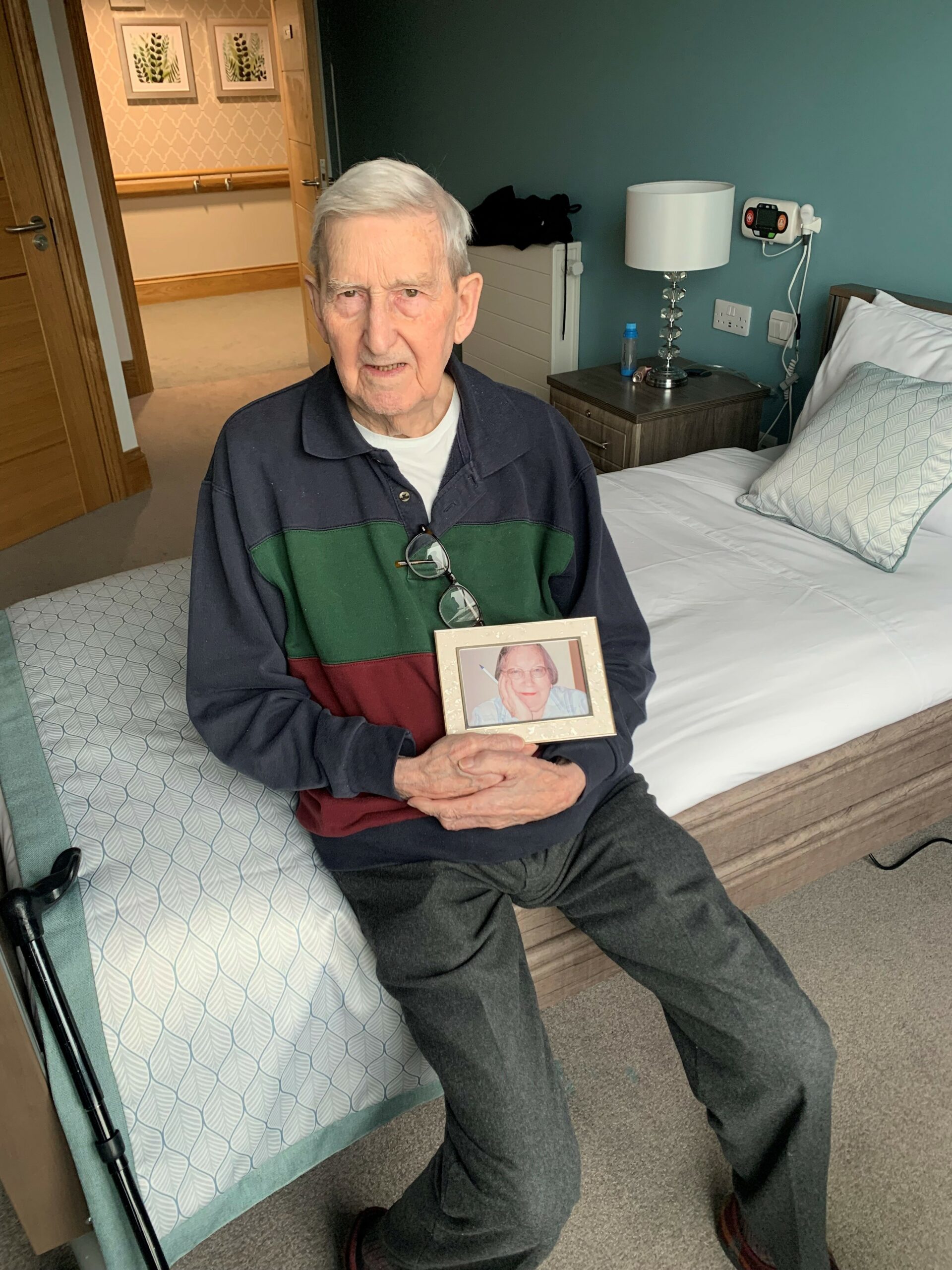 A male resident sat on his bed with a photo frame.