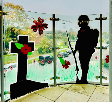 Handmade Remembrance Day display at Valerian Court Care Home, featuring tissue paper poppies, knitted freefalling poppies, and painted tributes including soldiers and planes.