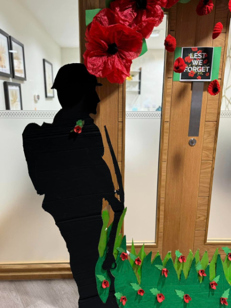 Handmade Remembrance Day display at Valerian Court Care Home, featuring tissue paper poppies, knitted freefalling poppies, and painted tributes including soldiers and planes.