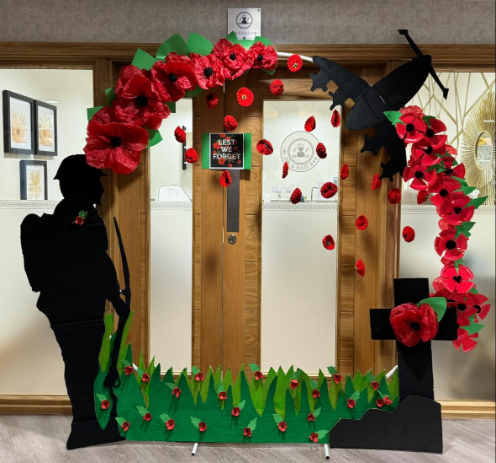 Handmade Remembrance Day display at Valerian Court Care Home, featuring tissue paper poppies, knitted freefalling poppies, and painted tributes including soldiers and planes.