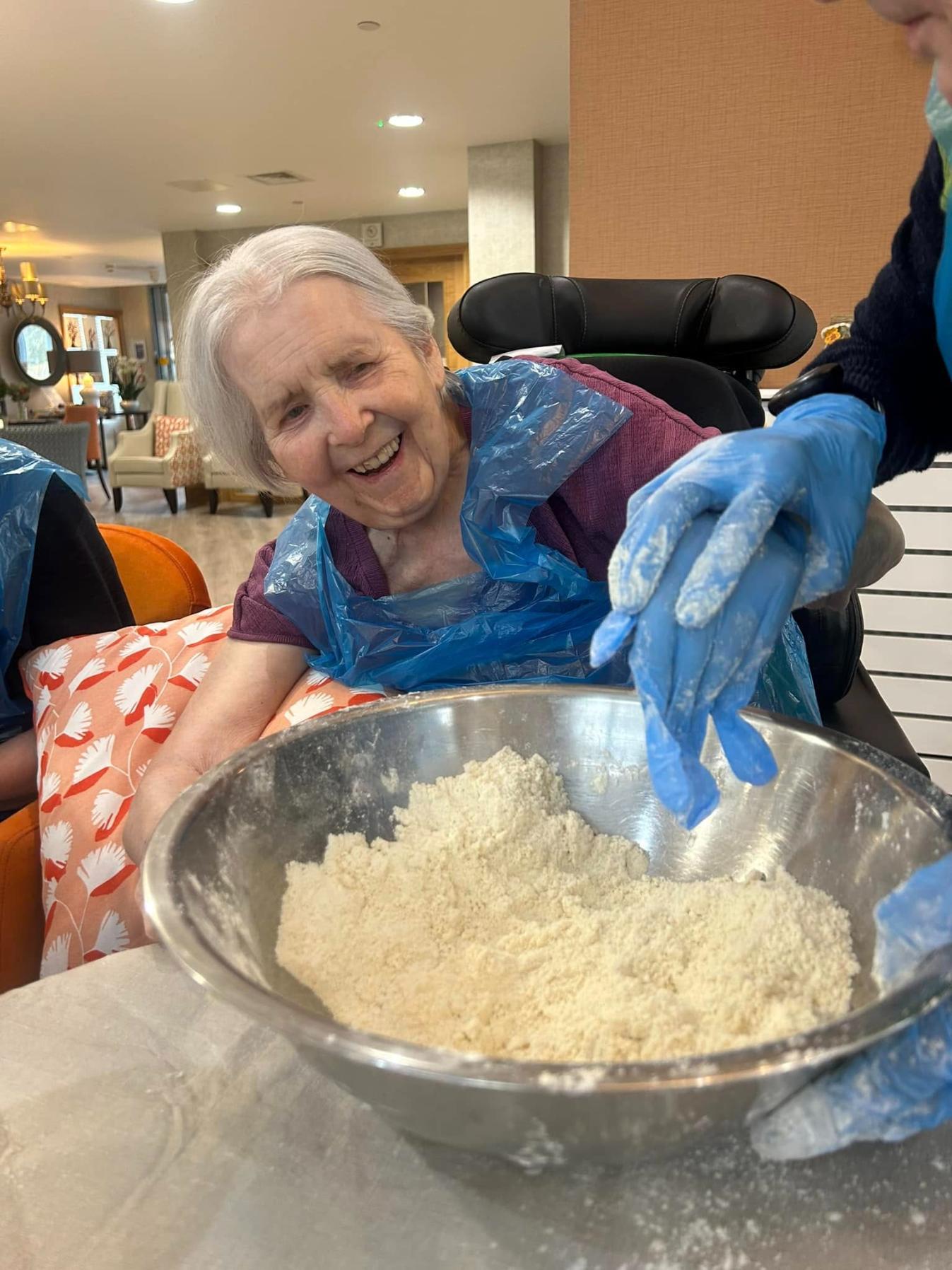 resident smiling adding flour to a bowl