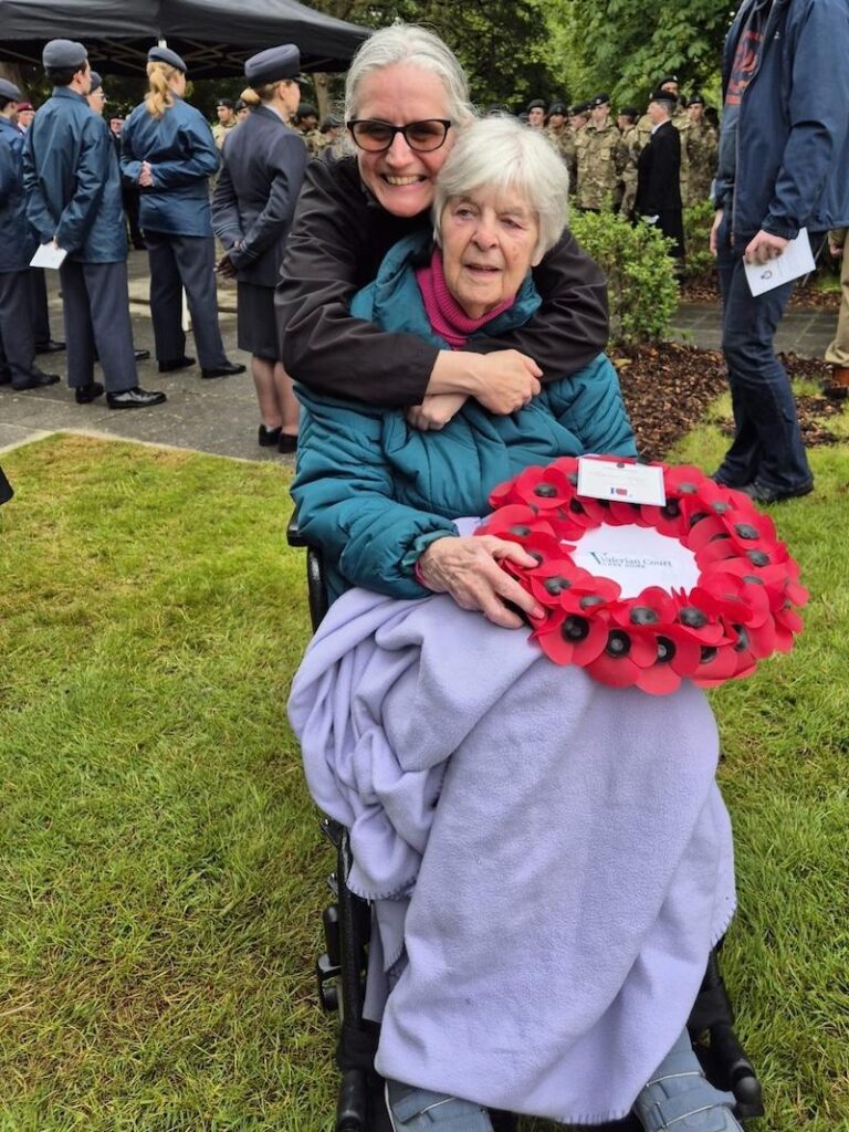 resident and carer with poppy wreath