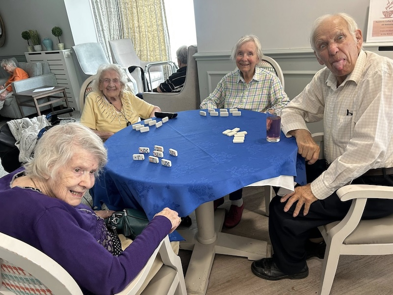 residents sat around a table playing dominoes together
