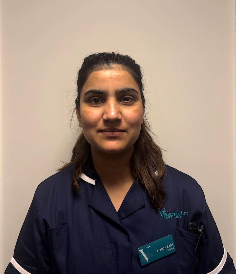 Female with brown hair and wearing a navy nursing uniform having a headshot for the team page