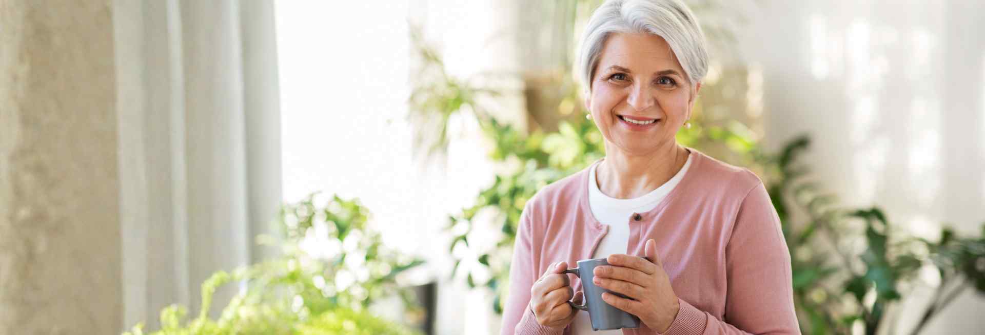 elderly woman smiling with a mug in her hand