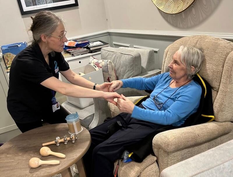 resident and carer holding hands and smiling at each other
