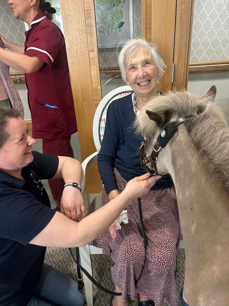 resident smiling sat with a therapy pony