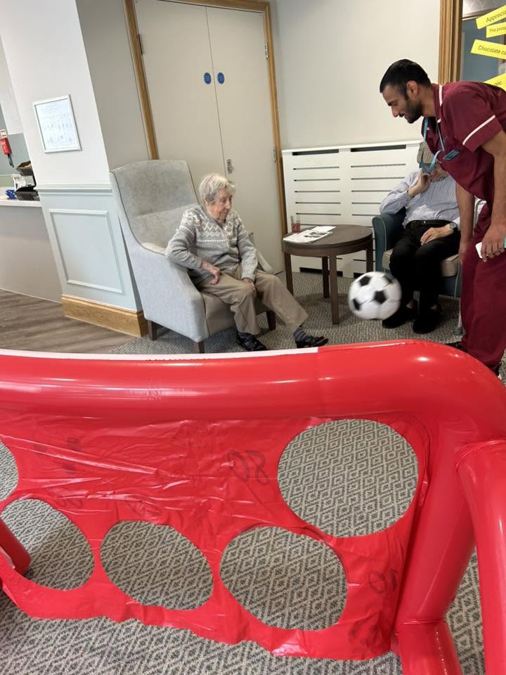 resident and a carer with a football in the lounge