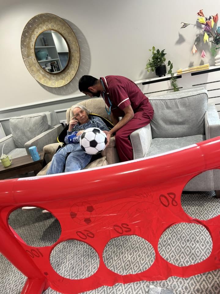 resident and a carer with a football in the lounge