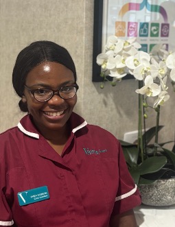 lady in a red care uniform posing for staff photo