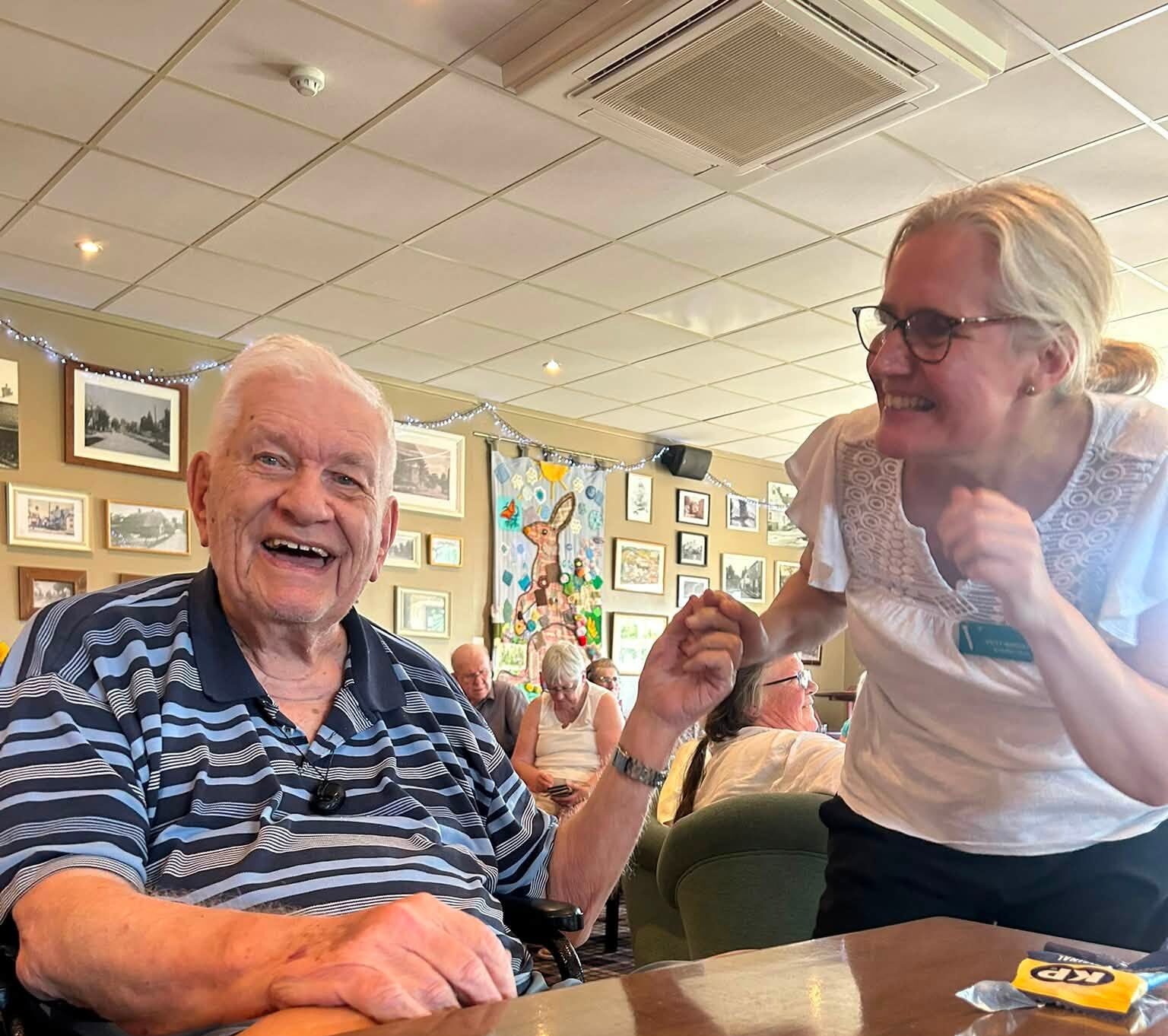 staff holding an older mans hand both smiling