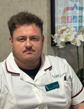 man in a white care uniform posing for staff photo