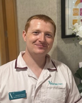 man in a white care uniform posing for staff photo