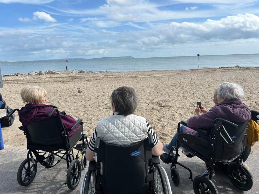 residents in wheelchairs sat by the beach