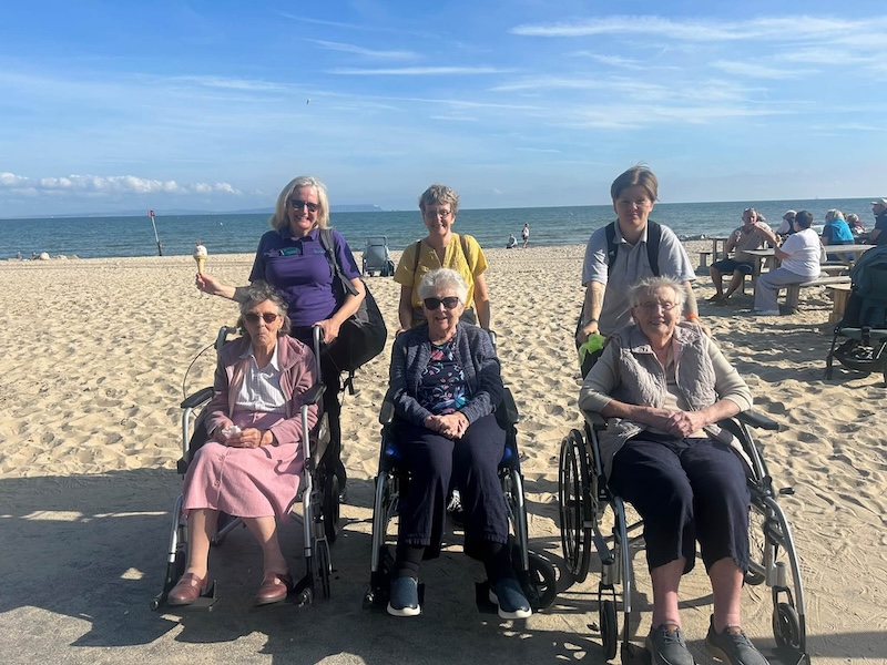residents and carers at the beach with ice cream